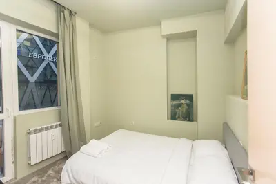 a white bedroom with a bed and a window at Elegant 2bdr Apartment with a Balcony in Sofia