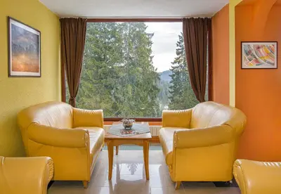 two chairs and a table in a room with a window at Kamena Pamporovo in Pamporovo