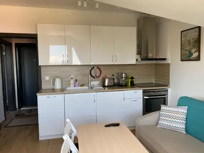 a kitchen with white cabinets and a table and a couch at Lovely Аpartment in IGLIKA 2,Borovets in Borovets