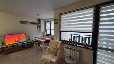 a living room with a flat screen tv and a table at Borovets Cozy Mountain Apartments in Borovets