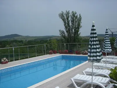 a swimming pool with lounge chairs and an umbrella at Apartament Fantasy Hisarya in Hisarya
