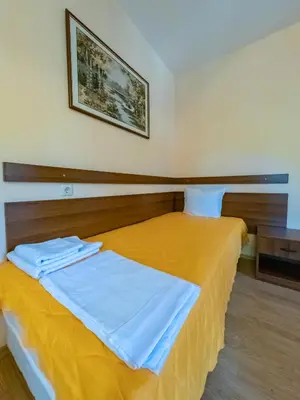 a bedroom with a bed with a yellow bedspread at Почивна база 