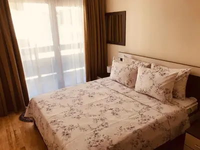 a bedroom with a bed with a floral bedspread and a window at Marina Apartments - One Bedroom in Bansko