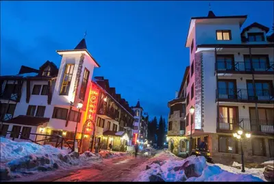 a group of buildings on a snowy street at night at Apartment in Castle 1 in Pamporovo