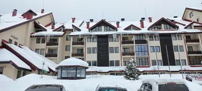 a large apartment building with snow on the roof at Мезонет Лапландия in Pamporovo