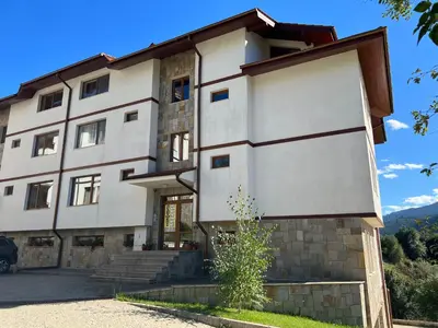 a large white building with a staircase in front of it at Ani's Guest House in Chepelare