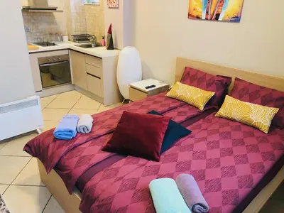 a bedroom with a bed with pillows and a kitchen at Private Studio Center Opera and Nevski Cathedral in Sofia