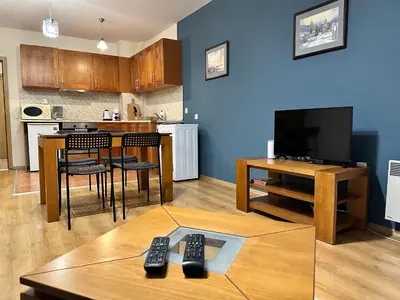 a living room with a television and a table with remote controls at Pirin place private apartment in Bansko