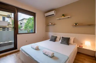 a bedroom with a bed and a large window at Bright 1BDR Apartment with a Balcony in Sofia