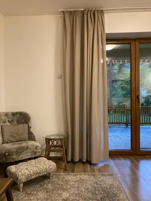 a living room with a chair and a sliding glass door at Вила Ренесанс Костенец in Kostenets Village