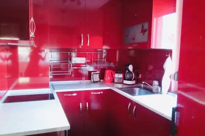a red kitchen with a sink and red cabinets at Mia's Apartment, Stylish one-bedroom apartment in Sofia