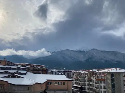 a city with snow covered roofs and buildings and mountains at CEDAR LODGE NEXT TO LIFT ONE BEDROOM APARTMENT in Bansko