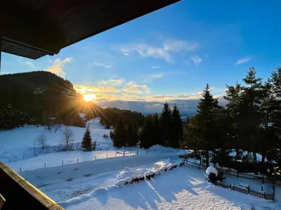 a winter view of a snow covered slope with the sun setting at Smolyan Lakes Apartment / Апартамент Смолянски езера in Smolyan