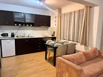 a kitchen and living room with a table and a couch at St. Anastasia Apartments in Bansko