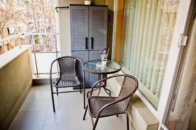 a table and chairs on a balcony with a window at Sunflower Apartment City Center in Plovdiv