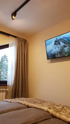 a bedroom with a bed and a tv on the wall at PinePino Borovets, aparthotel Borovets Gardens A60 in Borovets