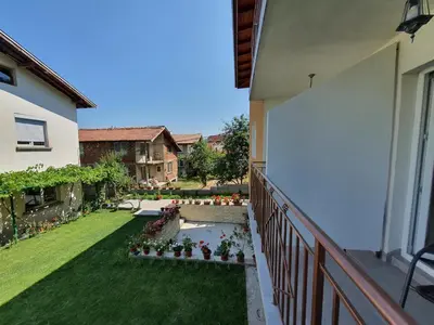 a balcony of a house with a yard with flowers at Дамяновата къща in Sapareva Banya