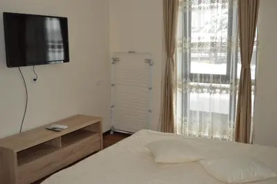 a bedroom with a bed and a television and a window at Grand Bansko D104 APARTMENT in Bansko