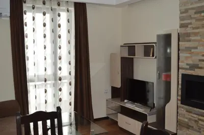 a living room with a glass table and a television at Grand Bansko D104 APARTMENT in Bansko