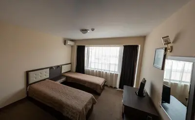 a hotel room with two beds and a window at Хотел България Петрич in Petrich