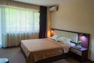 a bedroom with a bed and a large window at Хотел България Петрич in Petrich