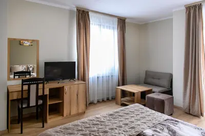 a bedroom with a bed and a desk with a television at Семеен хотел При Вергил in Sapareva Banya