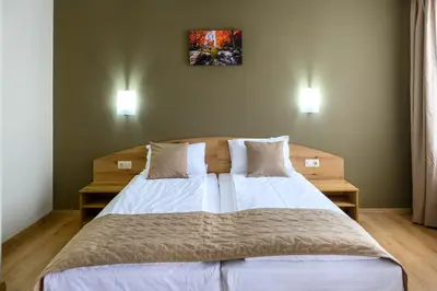 a bedroom with a large bed with white sheets and pillows at Семеен хотел При Вергил in Sapareva Banya