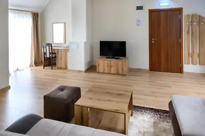 a living room with a couch and a television at Семеен хотел При Вергил in Sapareva Banya