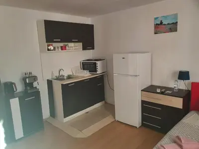 a small kitchen with a refrigerator and a microwave at Тих двустаен самостоятелен апартамент с двор,до площада на Сандански in Sandanski