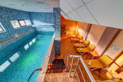 a swimming pool in a building with yellow chairs at Skyday Penthouse Deluxe at Oak Residence in Smolyan