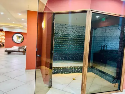 a glass shower in a room with a tile wall at Ardo Spa Hotel and Restaurant in Sarnitsa