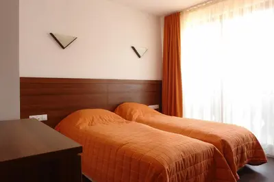 a bedroom with two beds and a table and a window at Winslow Infinity Aparthotel in Bansko
