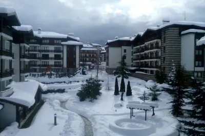 a courtyard covered in snow with buildings and trees at Winslow Infinity Aparthotel in Bansko