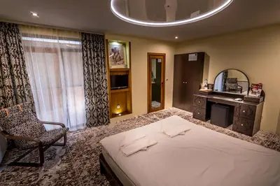a bedroom with a bed and a chair and a mirror at Tihiat Kut Complex in Kyustendil