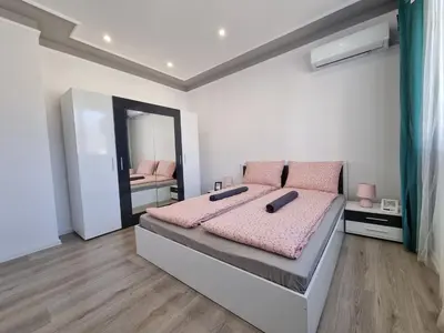 a bedroom with a bed with pink sheets and a mirror at Luxury two bedroom Crown apartament in Botevgrad