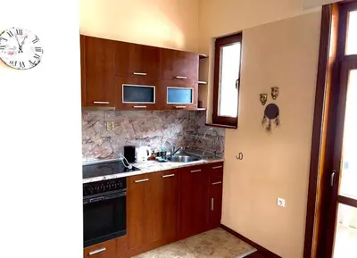 a kitchen with wooden cabinets and a sink at Апартаменти за гости ,,Friends