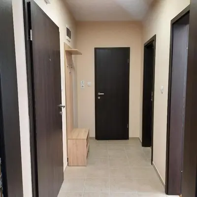 a hallway with two black doors and a tile floor at Апартамент Лидия in Chepelare