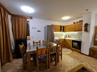 a kitchen with a table and chairs and a refrigerator at Pirin Golf Apartment HOME with private garden in Bansko