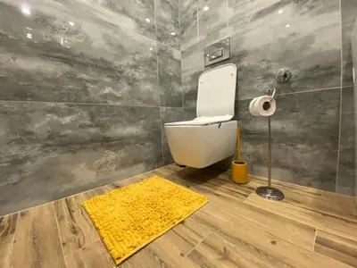 a bathroom with a toilet and a yellow rug at DV13 Luxury Suite Sofia Center in Sofia