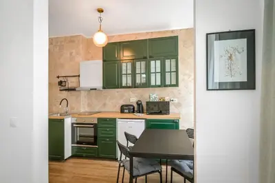 a kitchen with green cabinets and a table with chairs at Floral Studio Retreat in Sofia City Center by Flat Mаnager in Sofia