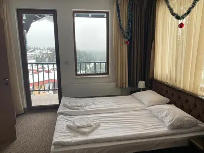 a hotel room with two beds and two windows at GrandView Apartment Grand Monastery in Pamporovo