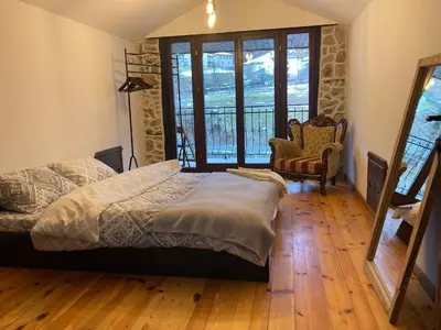 a bedroom with a bed and a large window at Къща Александрова с басейн вътрешен и отопляем in Arda