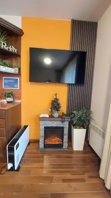 a living room with a fireplace with a tv on the wall at Сладко студио в Пирин с голф и СПА комплекс in Razlog