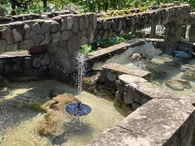 a fountain in a pond with a stone wall at Самостоятелни стаи в къща за гости Балкан in Ribarica