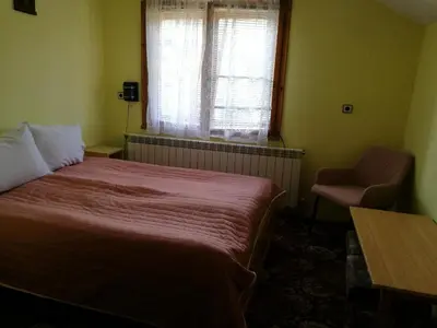 a bedroom with a bed and a chair and a window at Самостоятелни стаи в къща за гости Балкан in Ribarica