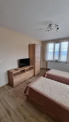 a hotel room with two beds and a television at Родопска къща за гости с.ЧАЛА in Chala