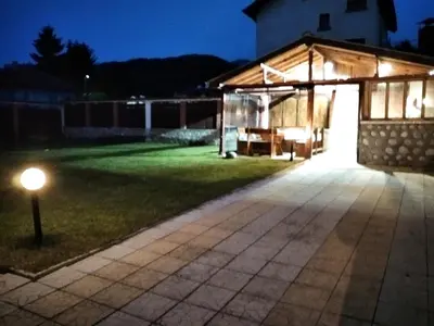 a lit up garage at night with a light on the grass at Къща за гости Релакс-Рaдуил in Raduil