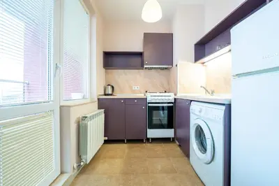 a kitchen with purple cabinets and a washer and dryer at Lovely apartment in Studentski grad in Sofia