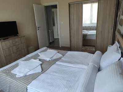 a bedroom with two beds with white sheets and a mirror at Апартамент Четири сезона 2 in Velingrad