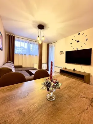 a living room with a table and a clock on the wall at Petkovi Аpartments, Borovets Gardens - One-bedroom and Two-bedroom apartments in Borovets